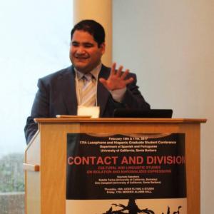 Photo of man standing at podium, wearing a suit.